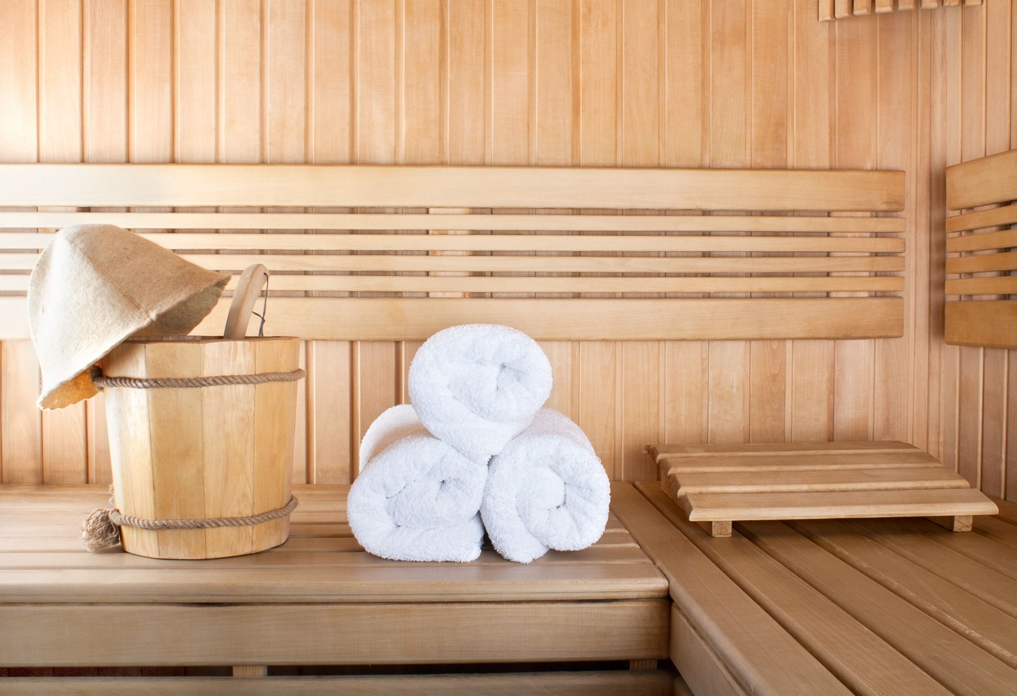 Traditional wooden sauna for relaxation with bucket of water and set of clean towels